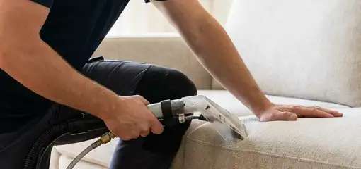 Professional upholstery cleaner deep-cleaning a fabric sofa with a handheld extraction tool, Overland Park, KS.
